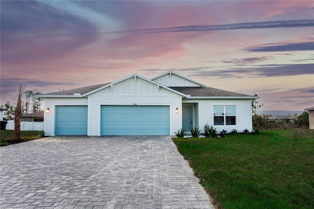 single story home with an attached garage, fence, decorative driveway, board and batten siding, and a front yard