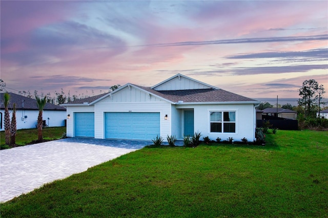 ranch-style home featuring decorative driveway, roof with shingles, an attached garage, board and batten siding, and a front lawn