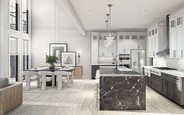 kitchen featuring tasteful backsplash, a center island with sink, glass insert cabinets, appliances with stainless steel finishes, and a sink