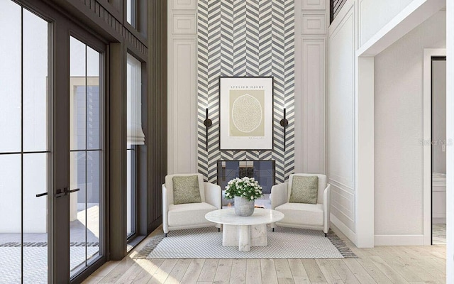 living area with light wood-style flooring, an accent wall, baseboards, and a fireplace