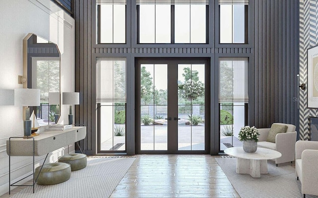 doorway to outside featuring a towering ceiling, plenty of natural light, and hardwood / wood-style floors