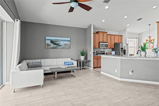 living room with recessed lighting, visible vents, baseboards, and ceiling fan with notable chandelier