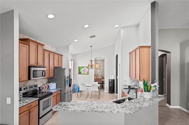 kitchen with arched walkways, stainless steel appliances, vaulted ceiling, and a sink