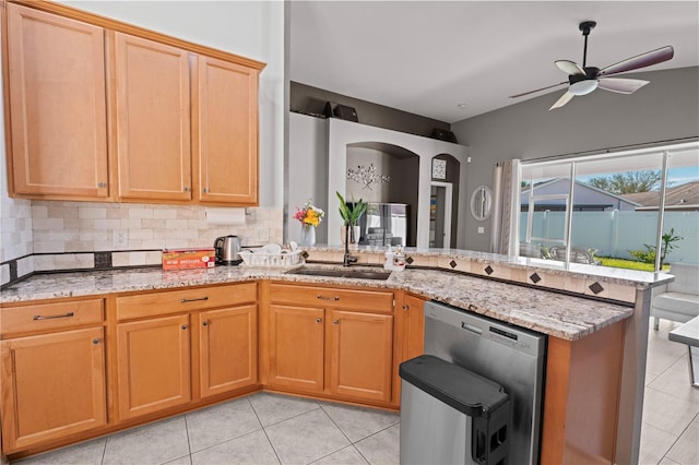 kitchen featuring light stone counters, a peninsula, a sink, decorative backsplash, and dishwasher