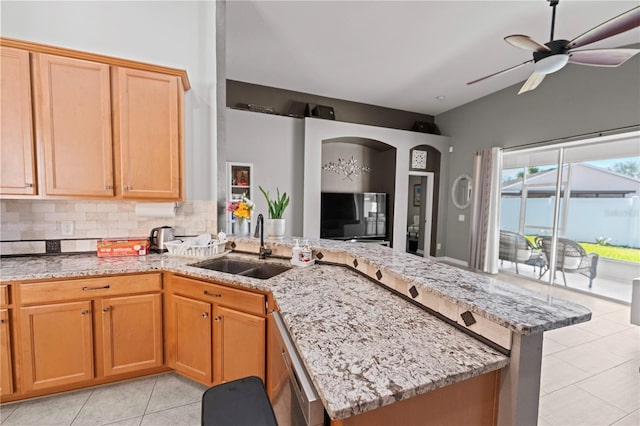 kitchen with a peninsula, light stone counters, backsplash, and a sink