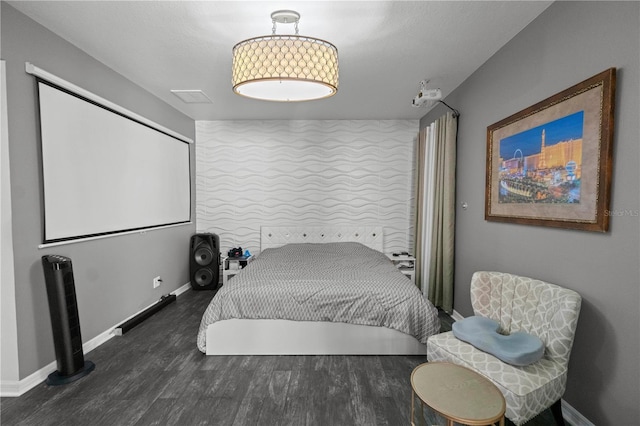 bedroom with an accent wall, baseboards, and wood finished floors