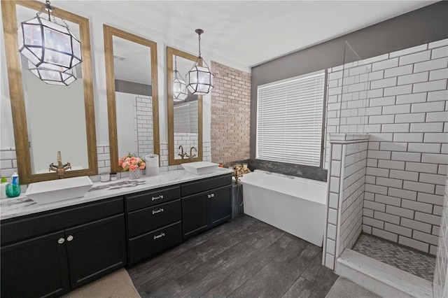 full bath with a freestanding bath, vanity, wood finished floors, a chandelier, and tiled shower