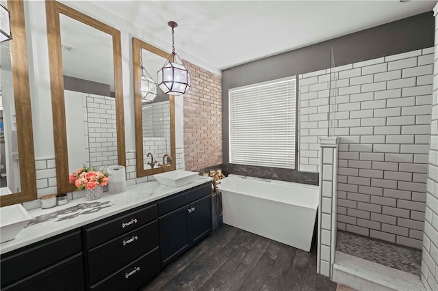 full bath with wood finished floors, vanity, tile walls, a freestanding bath, and a tile shower