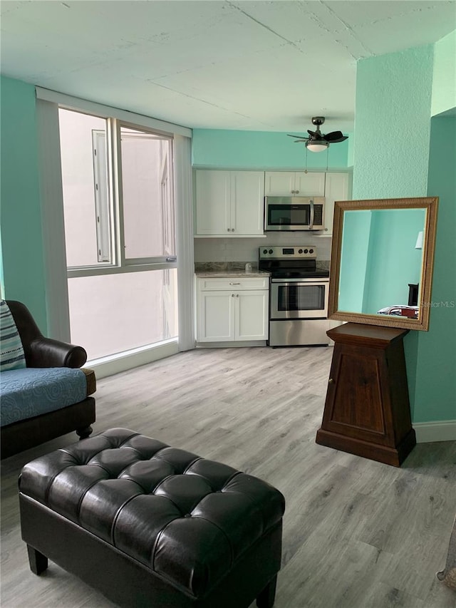 kitchen with baseboards, white cabinets, ceiling fan, stainless steel appliances, and light wood-type flooring