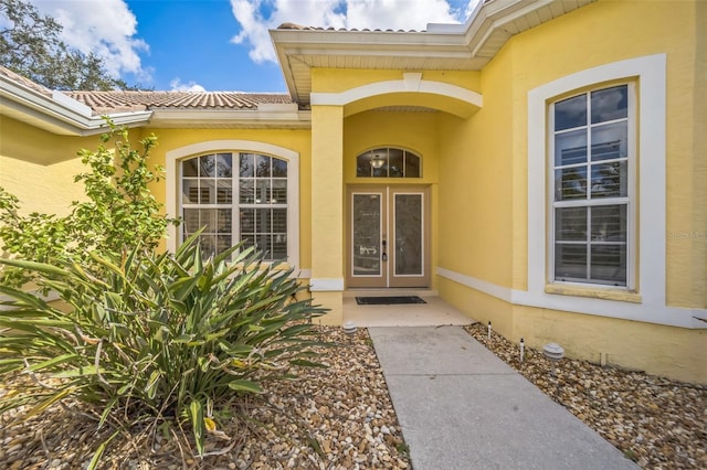 entrance to property featuring french doors, a tile roof, and stucco siding