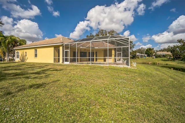 rear view of property featuring a lanai, a lawn, and stucco siding