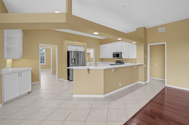 kitchen with light tile patterned floors, open shelves, light countertops, appliances with stainless steel finishes, and a peninsula