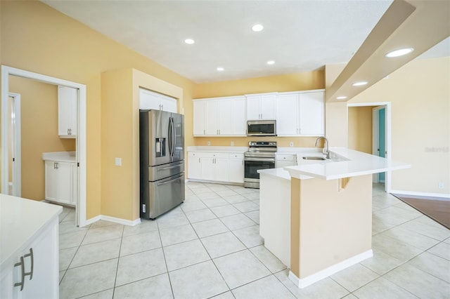 kitchen featuring light tile patterned floors, a peninsula, a sink, light countertops, and appliances with stainless steel finishes