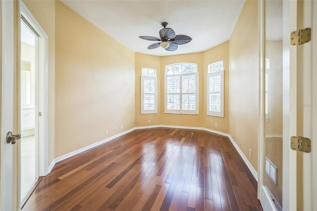 empty room featuring ceiling fan, dark wood-type flooring, visible vents, and baseboards