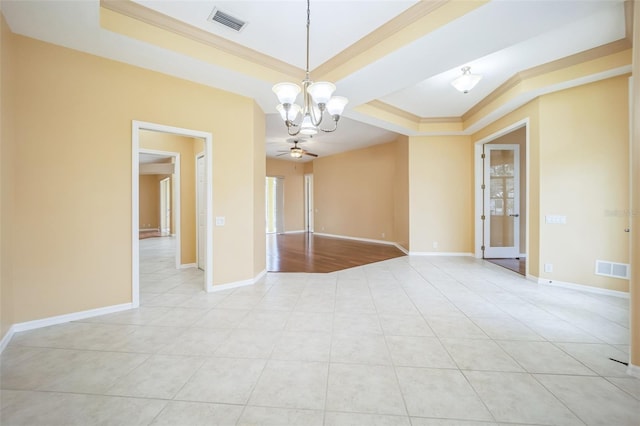 unfurnished room with a tray ceiling, visible vents, and crown molding