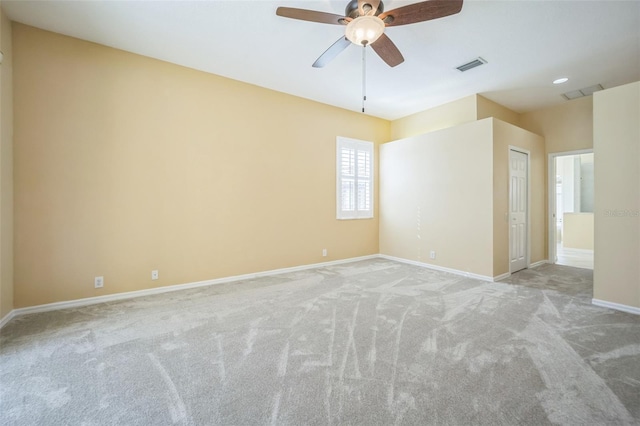 carpeted spare room featuring baseboards, visible vents, and ceiling fan