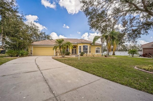 mediterranean / spanish house with driveway, an attached garage, fence, a front lawn, and stucco siding