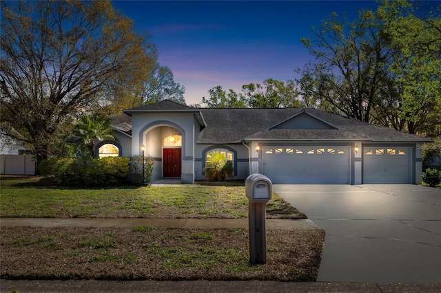 ranch-style house with a garage, driveway, a front lawn, and stucco siding