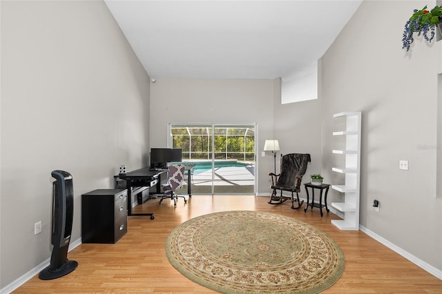 office space with a towering ceiling, light wood-style flooring, and baseboards