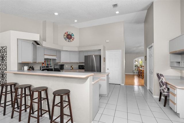 kitchen with visible vents, arched walkways, appliances with stainless steel finishes, a peninsula, and light countertops