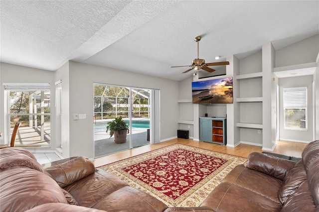 living area featuring built in shelves, lofted ceiling, and plenty of natural light