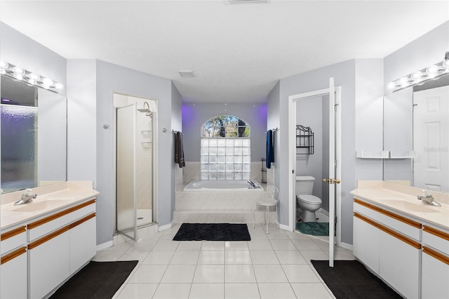 full bathroom with a bath, a shower stall, two vanities, and a sink