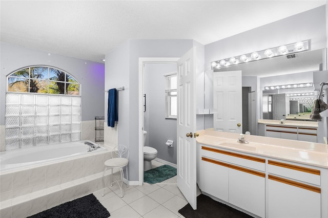 full bathroom featuring a textured ceiling, toilet, vanity, a bath, and tile patterned floors