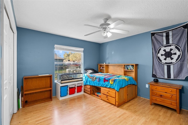 bedroom with a textured ceiling, a closet, wood finished floors, and a ceiling fan