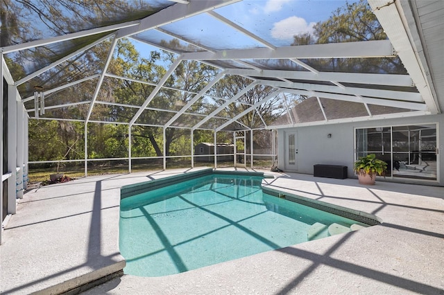 view of pool featuring an outbuilding, a patio, glass enclosure, a fenced in pool, and a storage unit