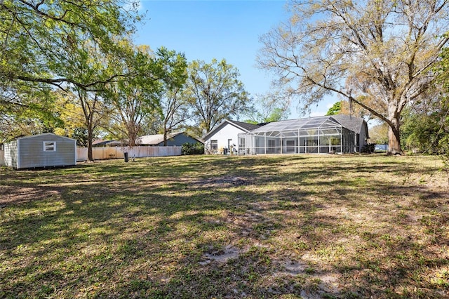 view of yard featuring glass enclosure, a shed, an outdoor structure, and fence