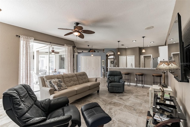 living room featuring arched walkways, a textured ceiling, and baseboards