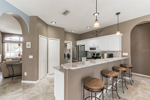 kitchen featuring visible vents, appliances with stainless steel finishes, arched walkways, and washing machine and clothes dryer