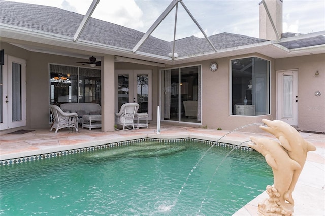 pool featuring french doors, a ceiling fan, glass enclosure, a patio area, and an outdoor living space