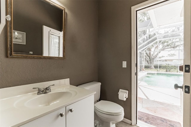 bathroom with a textured wall, vanity, and toilet