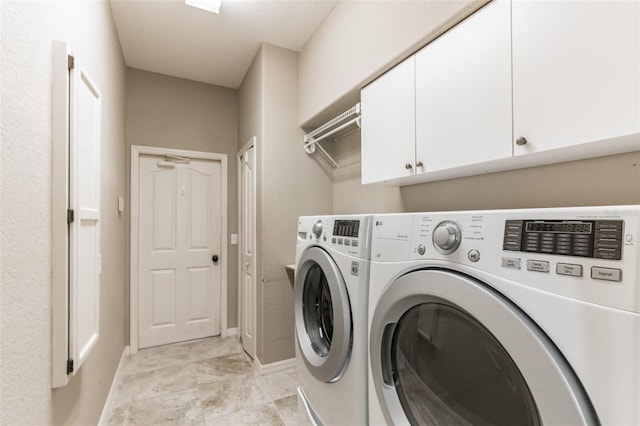 washroom with cabinet space, washer and clothes dryer, and baseboards