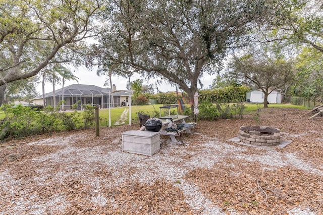 view of yard featuring a fire pit, glass enclosure, a shed, and an outbuilding