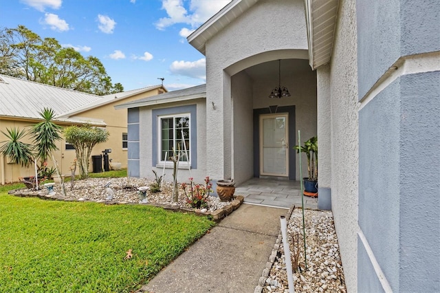 entrance to property featuring a yard and stucco siding