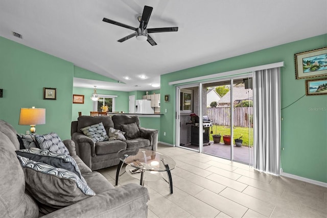 living area featuring light tile patterned floors, visible vents, a ceiling fan, vaulted ceiling, and baseboards
