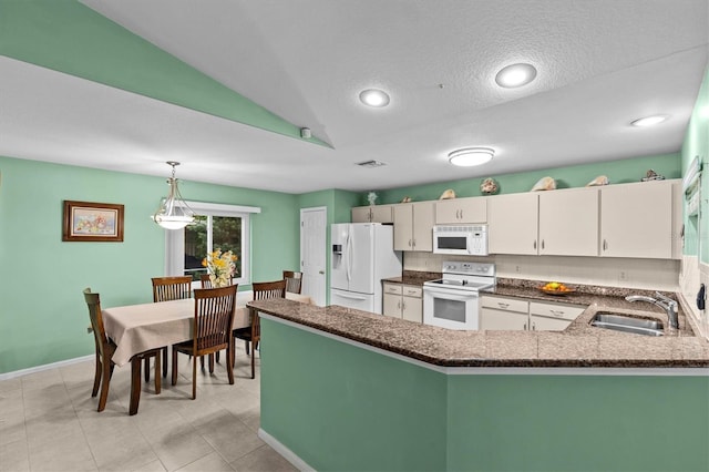 kitchen with white appliances, dark stone countertops, a peninsula, pendant lighting, and a sink