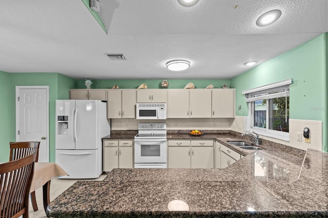 kitchen featuring white appliances, a sink, visible vents, decorative backsplash, and dark stone countertops