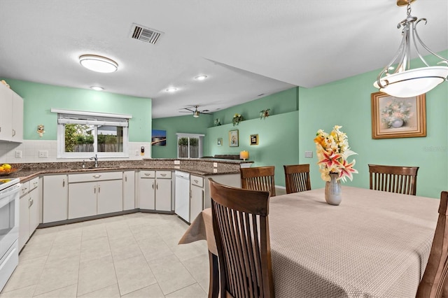 kitchen featuring white appliances, visible vents, white cabinets, dark countertops, and a sink