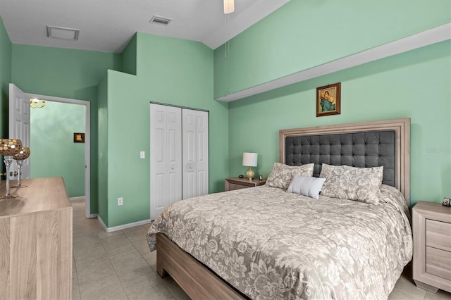 bedroom featuring light tile patterned floors, baseboards, visible vents, vaulted ceiling, and a closet