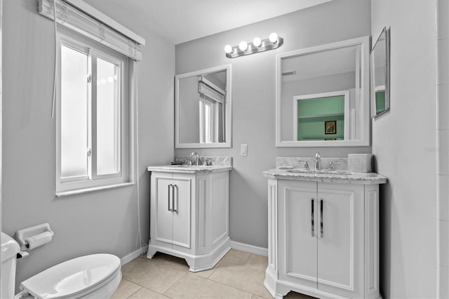 full bathroom with two vanities, a sink, toilet, and tile patterned floors