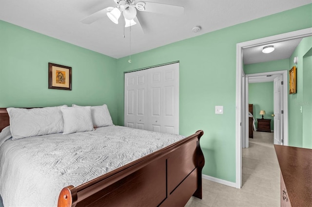 bedroom featuring ceiling fan, light tile patterned floors, a closet, and baseboards