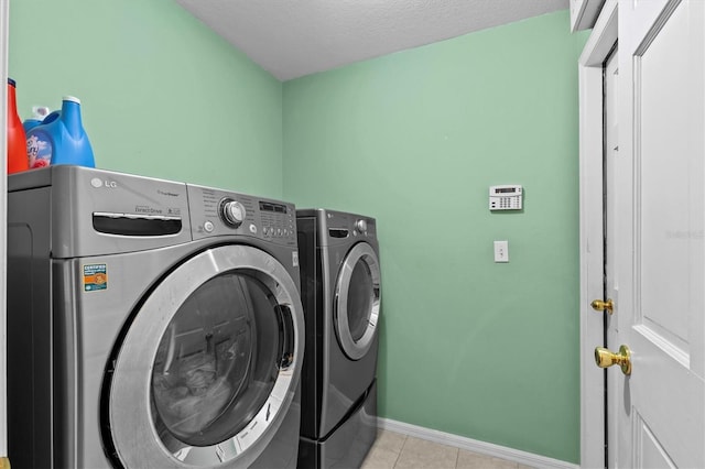 laundry room featuring laundry area, washing machine and dryer, light tile patterned floors, and baseboards