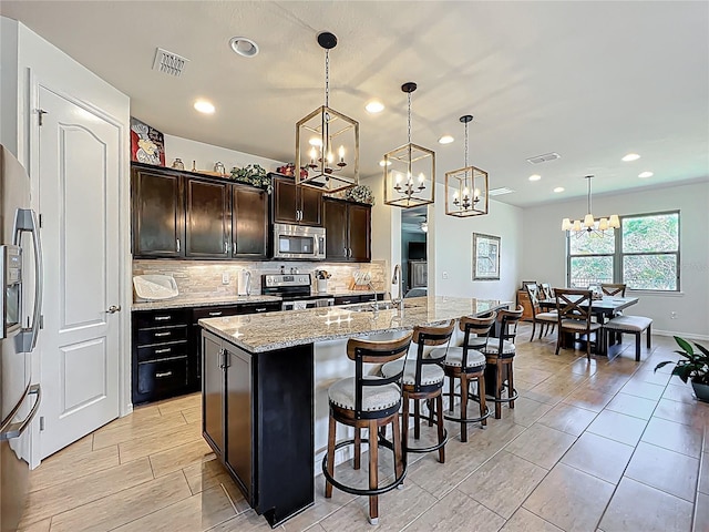 kitchen with visible vents, a sink, tasteful backsplash, appliances with stainless steel finishes, and light stone countertops