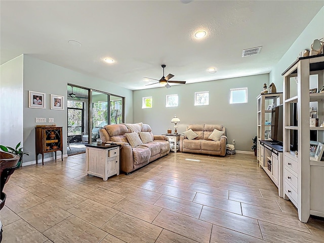 living area featuring baseboards, visible vents, and ceiling fan