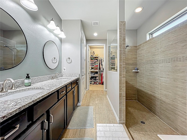 full bath featuring visible vents, wood finished floors, walk in shower, and a sink