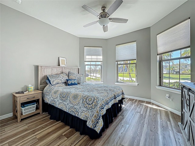 bedroom featuring ceiling fan, baseboards, and wood finished floors