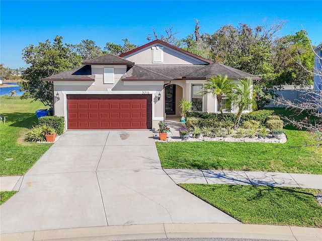 view of front of home featuring a front lawn, an attached garage, driveway, and stucco siding